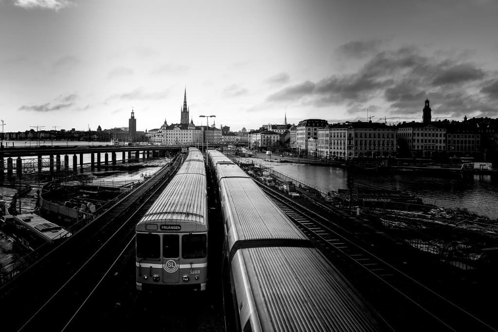 Pendeltåg mot Stockholms skyline med Stadshuset och Riddarholmen