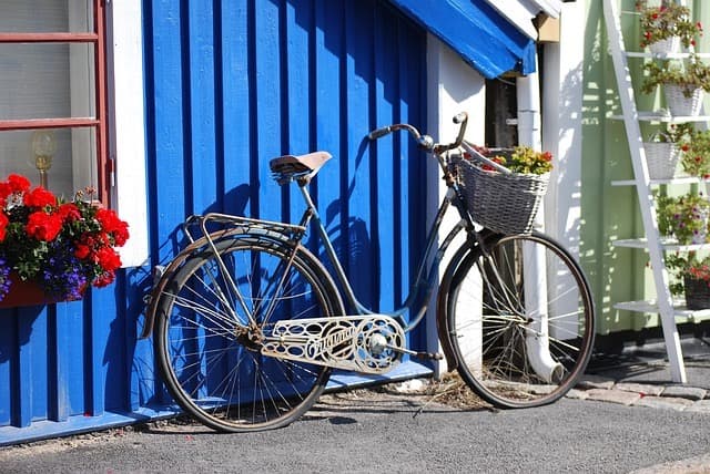 Cykel med blomkorg mot blå trävägg