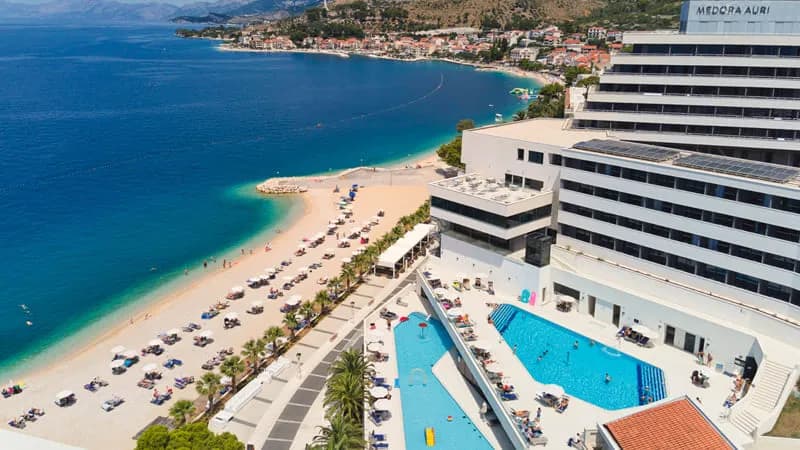 Hotell vid kroatiska kusten med pool, strand och bergskedja i bakgrunden